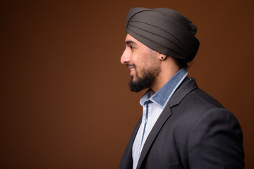 Poster - Young bearded Indian Sikh businessman wearing turban against bro