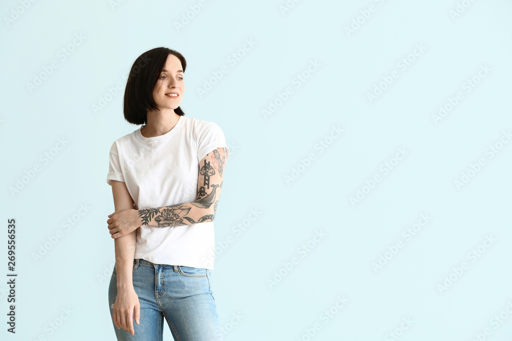 Beautiful tattooed woman on light background