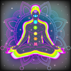 Meditating human in lotus pose in universe beside the stars. Yoga, esoterics; seven chakras and aura glow. Mandala background.