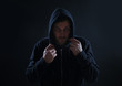 © New Africa - Mysterious man in hoodie on dark background. Dangerous criminal