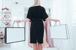Female shopper lifestyle. Women hobby. Luxury boutique. Back view of rich lady holding blank brand name mockup packages.