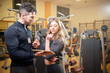 © Fabio Balbi - Man and woman looking at each other in gym. Athletic man holding digital tablet and looking at woman.