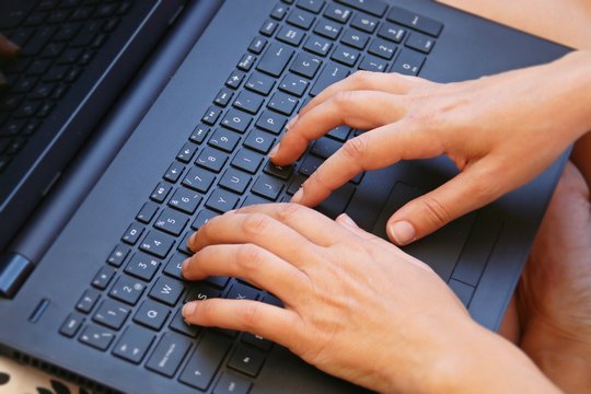 Using the laptop. Girl hands typing.