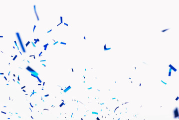 Confetti from crackers. Blue elements on a white background. Shot of confetti at a party. Festive mood. Serpentine, festive decor