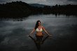 © REMEDIOS PUERTA/ADDICTIVE STOCK - Young woman in swimwear standing in calm water of pond in evening in nature