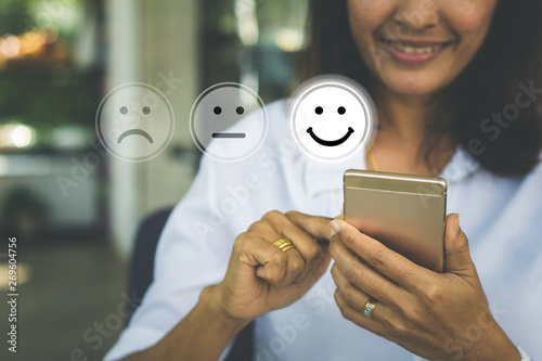 Photographie Businesswoman pressing face emoticon on virtual touch screen at smartphone