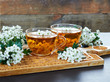 Pair of herbal healing flower tea from hawthorn bloom with blossom of  a tree nearby on wooden board on rustic background, closeup, copy space, alternative medicine concept