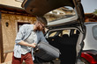 © Anatoliy Karlyuk - Travel, adventure, people and summertime concept. Outdoor shot of handsome trendy looking young man with stubble holding suitcase while putting his luggage in trunk, going to airport on car