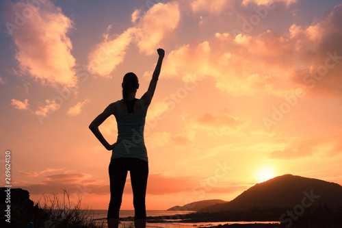 Fotografía silhouette of young strong victorious woman with fist in the air at sunset
