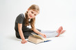 © briagin - Little girl photographed against white background wearing school uniform dress isolated sitting with open book