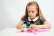© briagin - Little girl photographed against white background wearing school uniform dress isolated trying to solve geometric puzzle