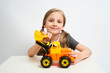 © briagin - Little girl photographed against white background isolated is playing with toy bulldozer