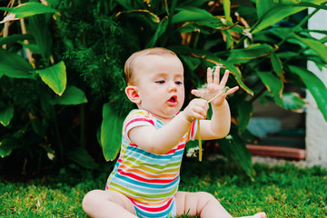 Baby putting in his mouth a flower of a garden, concept of dangers for babies.