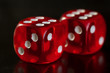 Closeup of a two red dice with a winning number on the top face on a black mirror surface