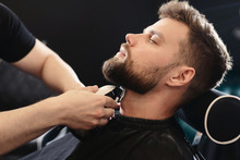 Getting Perfect Shape. Close-up Side View Of Young Bearded Man Getting Beard Haircut By Hairdresser Or Barber At Barbershop