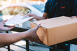 © wutzkoh - Young asian man smiling while delivering a cardboard box to the woman holding document to signing signature.