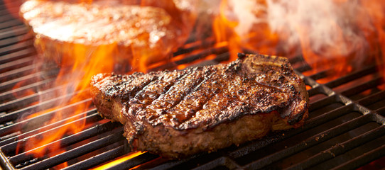 rib-eye steaks cooking on flaming grill panorama