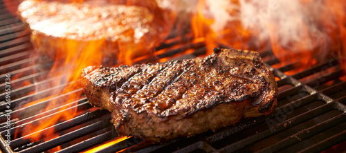 Fotografía rib-eye steaks cooking on flaming grill panorama