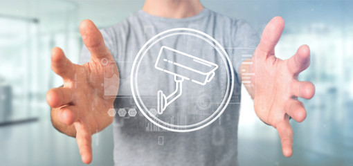 Poster - Businessman holding Security camera system icon and statistics data - 3d rendering