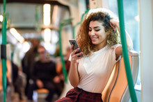 Arab Woman Inside Subway Train Looking At Her Smartphone