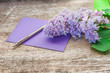 Gałązka liliowego bzu na drewnianym stole z kopertą i długopisem