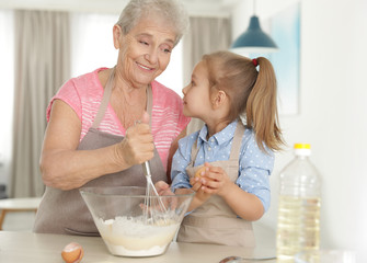 Poster - Cute girl and her grandmother cooking in kitchen