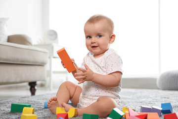 Poster - Cute baby girl playing with building blocks in room