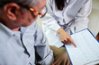 © DragonImages - Close-up of senior man and doctor with cardiogram on clipboard meeting in medical office at hospital, doctor explaining some facts about disease