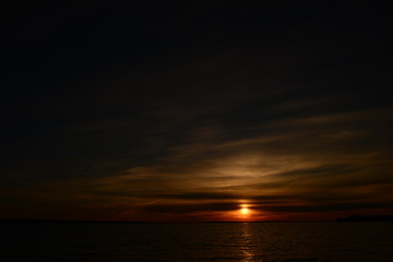 Sunset on the horizon a bright  of the sun circle in a cloudy sky in twilight darkness