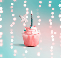 Celebratory cupcake with a decorative lit candle