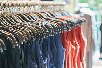 Wall Mural - Interior of fashion clothes store with t-shirts on hangers in red, blue and other colors.