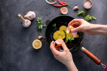 persons hand hold cracked egg and pour a yolk and protein in a frying pan to cook it, rustic styles