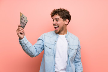 Wall Mural - Blonde man over pink wall taking a lot of money