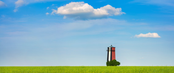 Wall Mural - spring landscape with alone lighthouse and clouds in blue sky