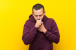 © luismolinero - Colombian man with sweatshirt over yellow wall is suffering with cough and feeling bad