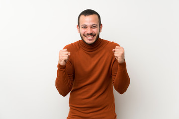 Wall Mural - Colombian man with turtleneck sweater celebrating a victory in winner position