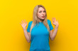 © luismolinero - Young blonde woman over isolated yellow background making doubts gesture