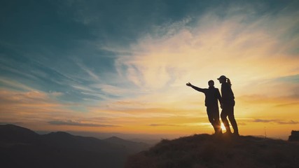 Wall Mural - the man and woman standing on the mountain with beautiful sunset
