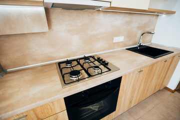 modern light interior. modern kitchen with steel hob. kitchen cabinets with wooden doors.