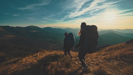 Wall Mural - the man and woman walking in the mountain on the sunset background. slow motion