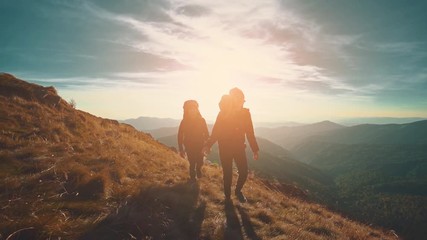 Wall Mural - the couple walking in mountains against the sunset background. slow motion