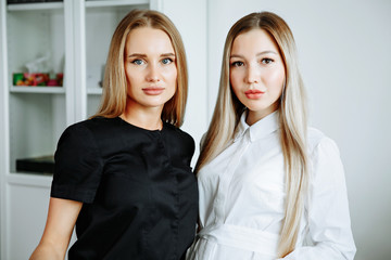 Two successful confident beauty salon female owners looking at camera. Cheerful female beautician is working with cosmetology. Two women crossed arms with confidence.