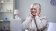 © motortion - Unhappy senior woman holding head, suffering from migraine disorder, health