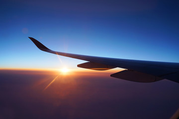 Wall Mural - red sunlight spreading on aerial cloud and land below airplane wing