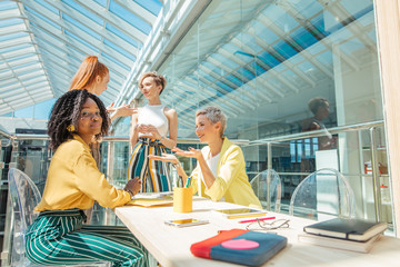 Wall Mural - blond woman gives advice on clothing , hair, behavior in society while afro woman looking at the camera