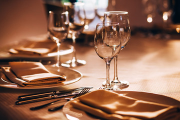 served table with white tablecloth. white plates, wine glass, fork, knife