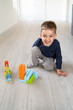 © Miljan Živković - Small boy playing with plastic brick block toys on the wooden floor at home