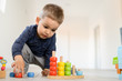 © Miljan Živković - Small boy playing with wood brain teaser toys on the wooden floor at home
