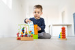 © Miljan Živković - Small boy playing with plastic brick block toys on the wooden floor at home