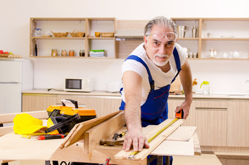 Aged contractor repairman working in the kitchen 